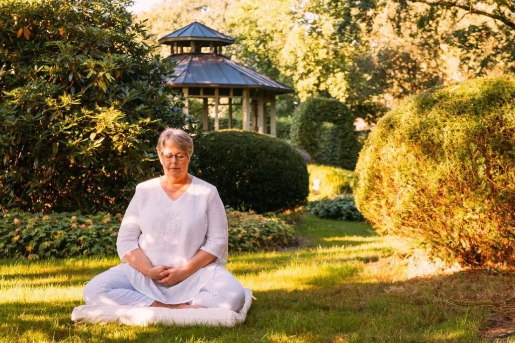 Doris Kirch sitzt in ihrem Garten und praktiziert Achtsamkeitsmeditation.